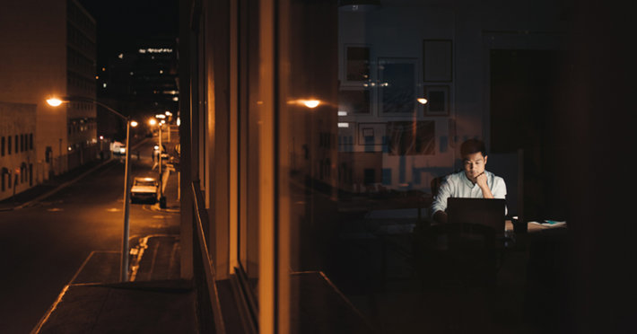 Night street and a man in the office, using computer